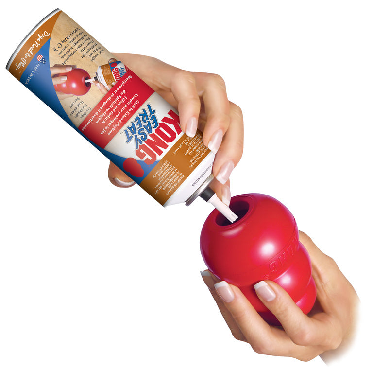 Hands dispensing KONG Easy Treat Peanut Butter into red KONG rubber toy supplied by Paw Branch