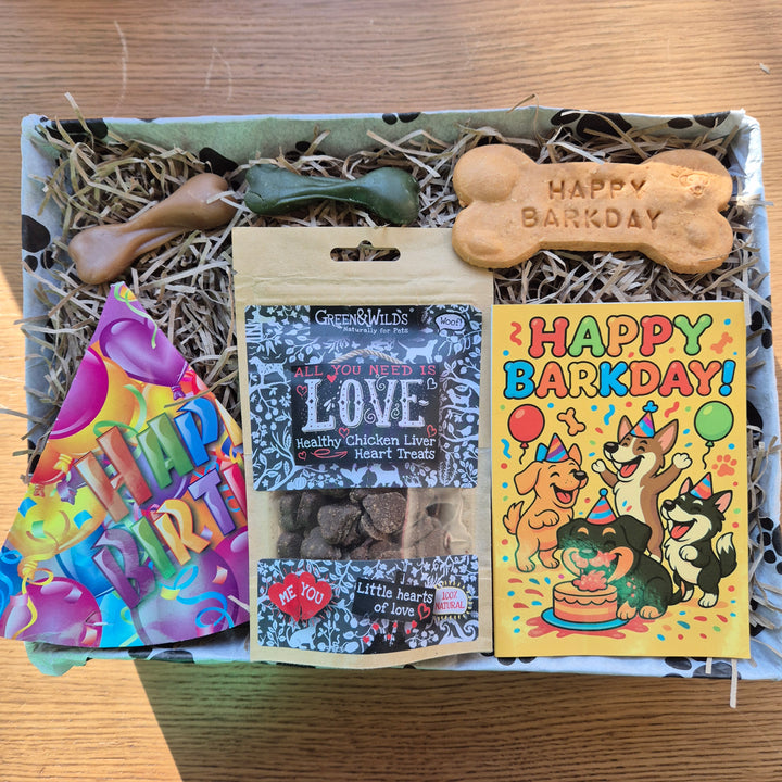 Dog birthday gift box with treats and a card on a wooden surface