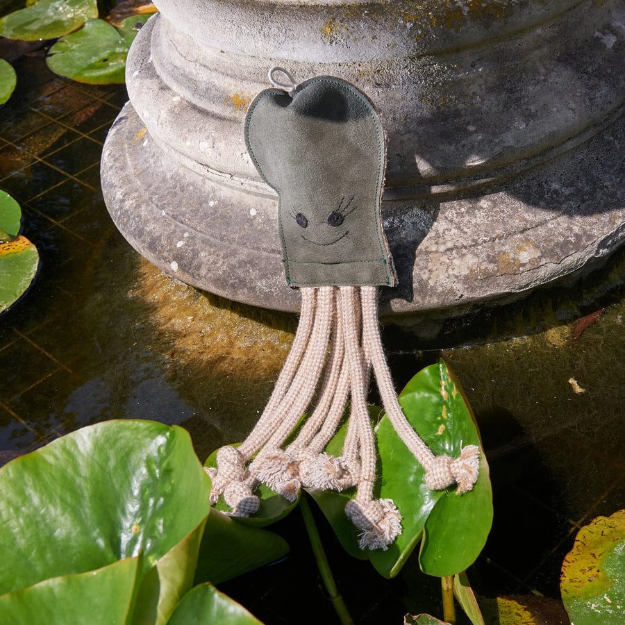 Olive the Octopus eco dog toy by Green and Wild’s for small and medium sized dogs photographed outdoors on stone fountain and-lilypad supplied by Paw Branch