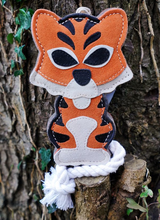 Detailed shot of the orange and black Tina the Tiger toy by Aurora Paws with a white rope hanging from the bark of a tree, supplied by Paw Branch.