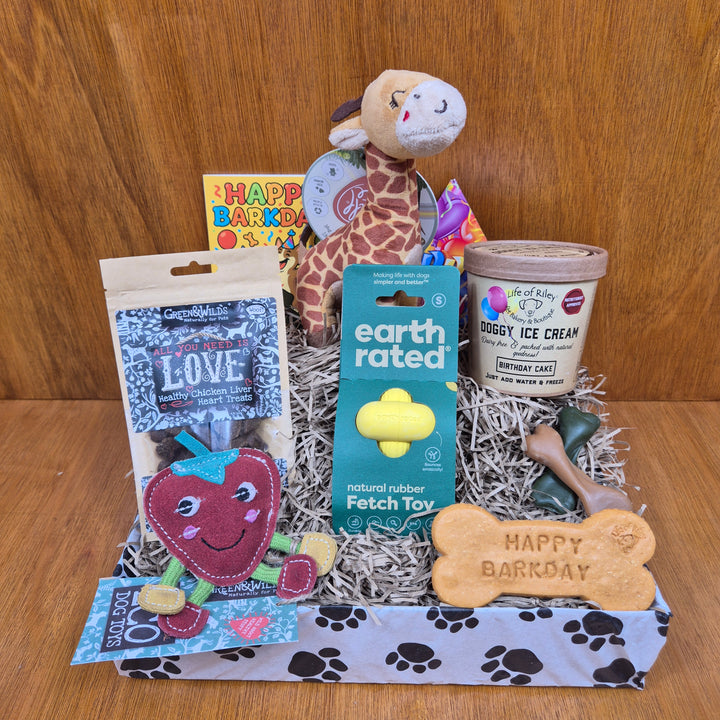 Dog  birthday gift basket with toys, treats, and a toy box on a wooden surface - Paw Branch